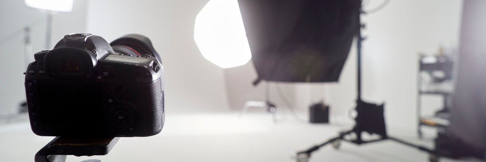 A camera on a tripod in a photography studio with softbox lights behind
