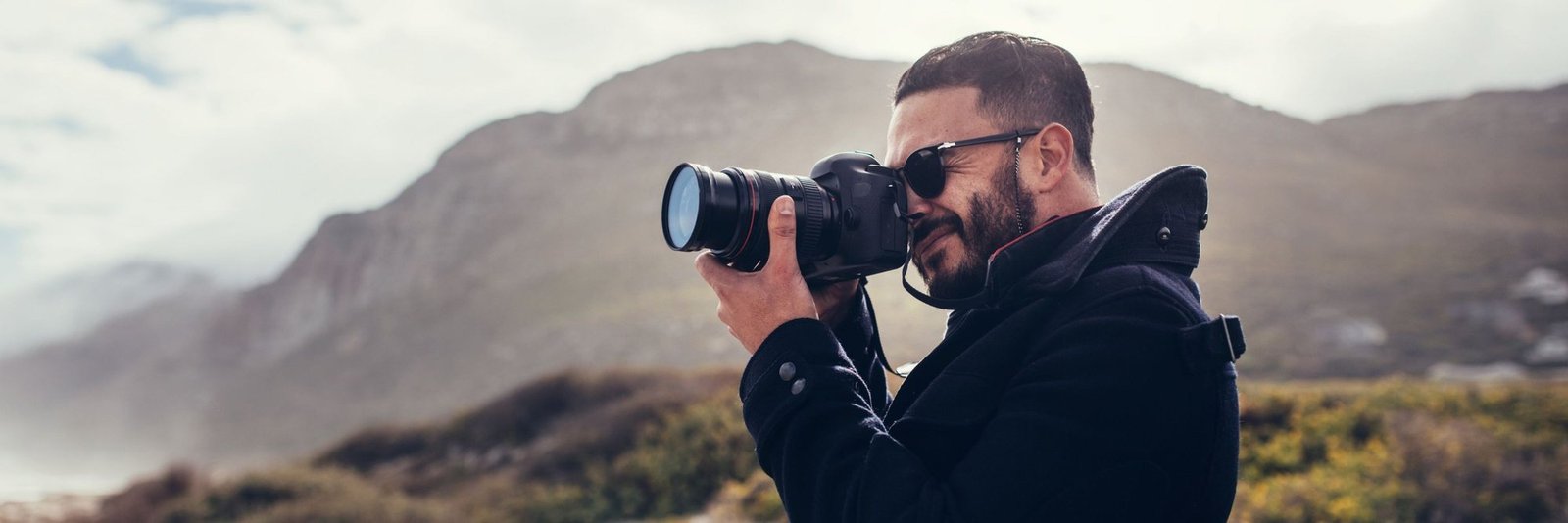A photographer raising his camera in the mountains above the Cape coast