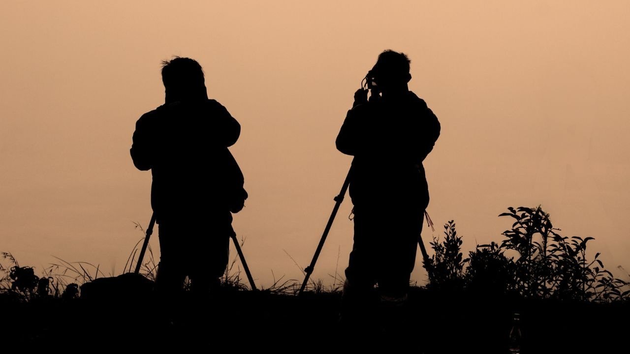 Two photographers with tripods in silhouette during a private lesson at sunrise
