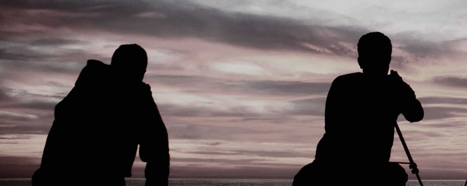 Two photographers in silhouette with a tripod against a dusk sky
